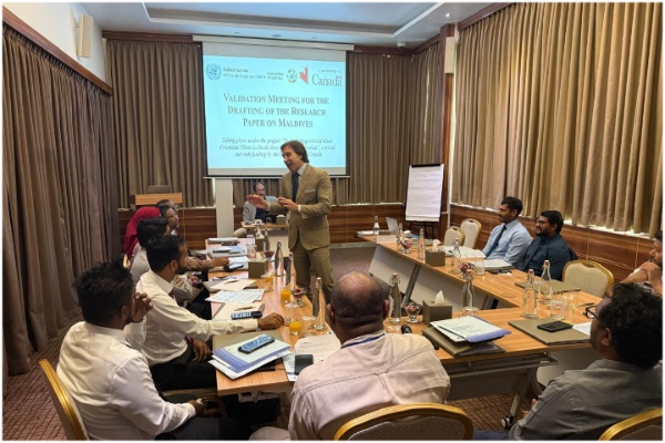 Participants looking towards the main speaker, with a screen in the background.