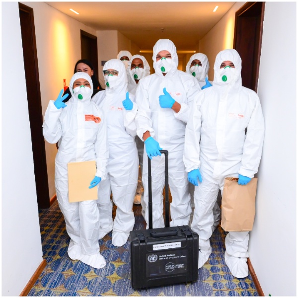 Participants wearing PPE kits posing for a photograph after engaging in a group exercise on crime scene investigations.
