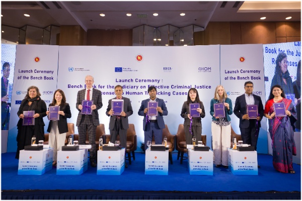 Senior officials holding up copies of the bench book on the dais.