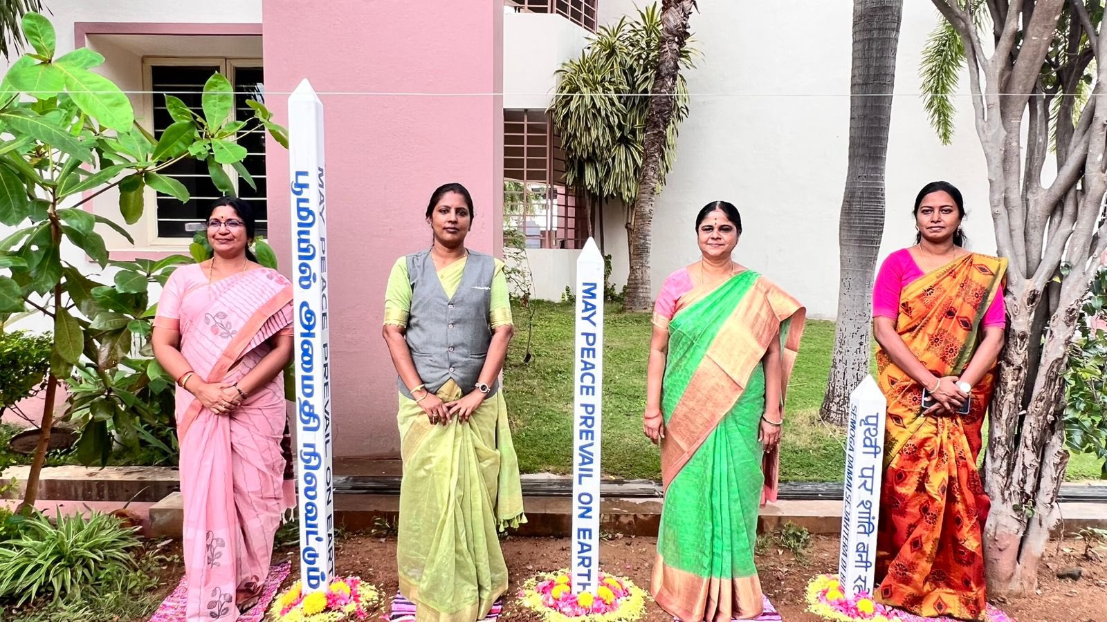 Educators standing in a peace garden with special pillars displaying messages of harmony