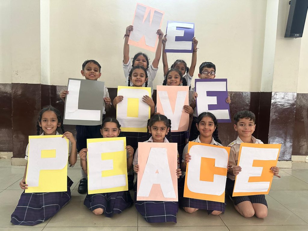 Students in a classroom holding up posters saying "I love peace"